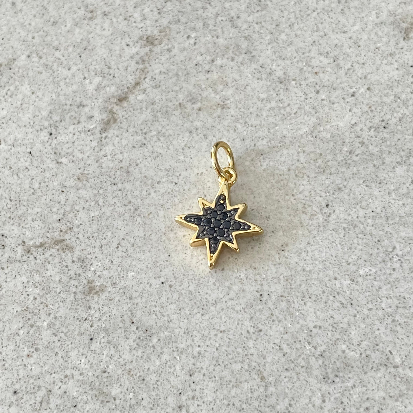 Gold star charm paved with black zircons