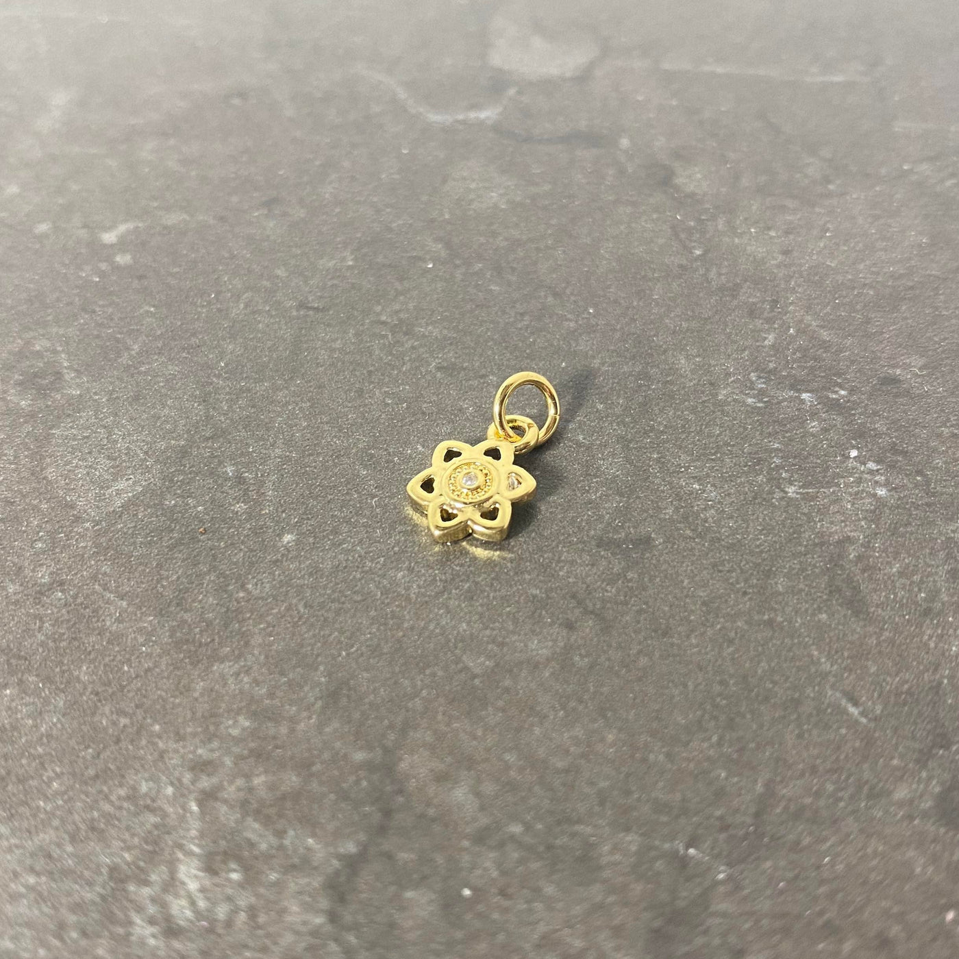 Gold floral style charm with shiny zircon made of brass